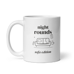 White 11 oz mug with handle on the left, showing Night Rounds, Sofa Edition lettering with a sofa, remote, mug and fictional chart. Supplier-generated mockup; not a physical sample.